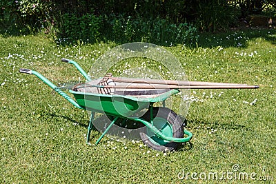Wheelbarrow with lawn rake and claw cultivator Stock Photo