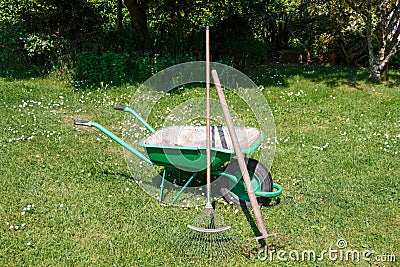 Wheelbarrow with lawn rake and claw cultivator Stock Photo