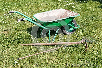 Wheelbarrow with lawn rake and claw cultivator Stock Photo