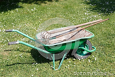 Wheelbarrow with lawn rake and claw cultivator Stock Photo