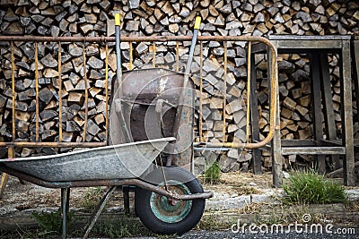 Wheelbarrows and wooden logs stored for winter on a country farm Stock Photo