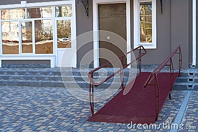 Wheelchair access ramp for entrance of residential multistory building, city street and tiles sidewalk Stock Photo