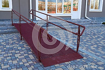 Wheelchair access ramp for entrance of residential multistory building, city street and tiles sidewalk Stock Photo