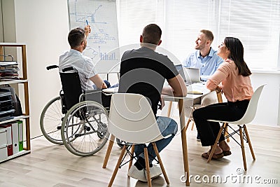 Wheelchair And Disability At Office. Giving Presentation Stock Photo