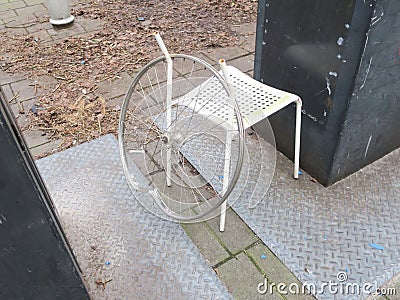 Wheelchair, wheel of a bicycle hanging on a white chair Stock Photo