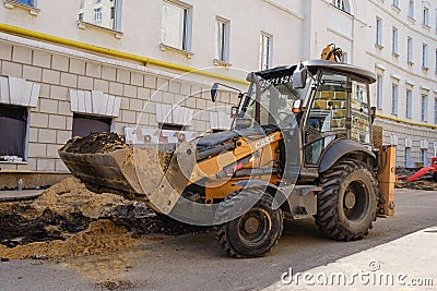 Wheeled compact excavator loader Case is working on the repair of urban communications Editorial Stock Photo