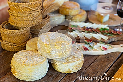 Wheels of hard goat cheese stacked on table during degustation Stock Photo
