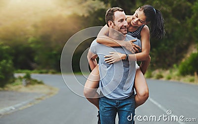 Where theres love, youll never walk alone. a happy young couple enjoying a piggyback ride outdoors. Stock Photo