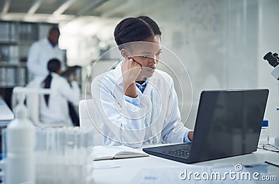 Where theres a why theres a way. a young scientist using a laptop while conducting research in a laboratory. Stock Photo