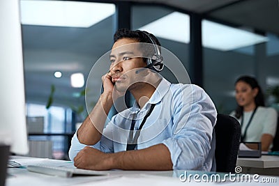 Wheres a call transfer when you need one. a young man using a headset and looking bored in a modern office. Stock Photo