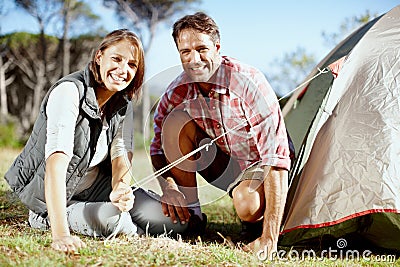 Wheres the peg. Portrait of a young couple setting up their tent. Stock Photo