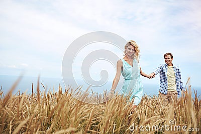 Wherever she leads, he will follow. a young couple in a field on a sunny day. Stock Photo