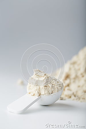 Whey protein isolate with a measuring spoon on a white background. Stock Photo