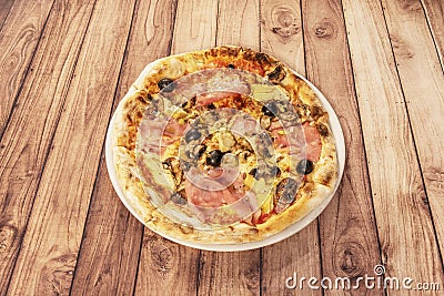 Whimsical Italian gastronomy pizza prepared with mozzarella cheese, oven-roasted Italian ham, artichokes Stock Photo