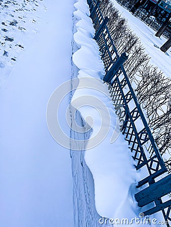 Whimsical overhanging wavy drifts blown with the wind through the fence Stock Photo