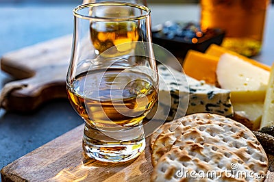 Whiskey and cheese pairing, tasting whisky glasses and plate with sliced cheeses Stock Photo