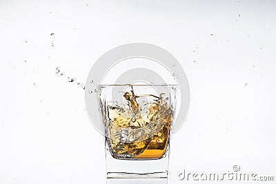 Whiskey with ice. Rum with ice. Brown brandy with ice. Three ice cubes in a glass with alcohol. Stock Photo