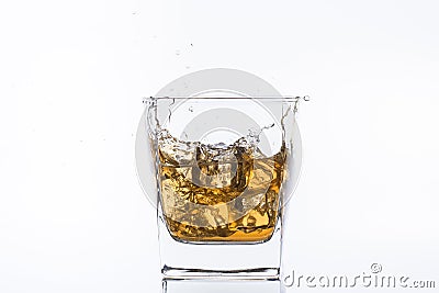 Whiskey with ice. Rum with ice. Brown brandy with ice. Three ice cubes in a glass with alcohol. Stock Photo