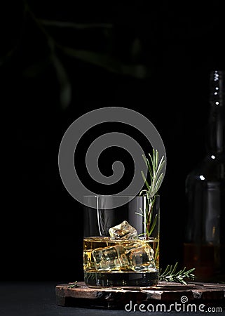 Whiskey, scotch or bourbon glass with fresh rosemary, ice cubes on black background Stock Photo