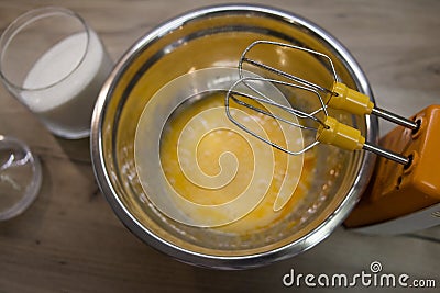 whisks of electric mixer in front of sugar and eggs in a bowl Stock Photo
