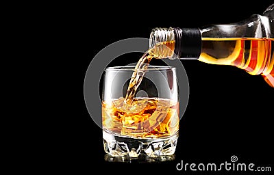 Whisky pouring from the bottle over black. Whiskey on the rocks Stock Photo