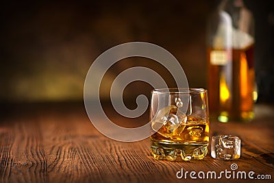 Whisky on the rocks. Glass of whiskey with ice cubes over wooden background Stock Photo