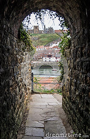 Stone arched passageway through historic wall with view on other side including Whitby Abby Editorial Stock Photo