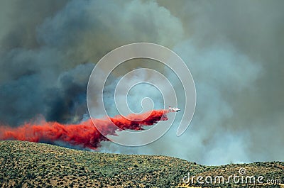 White Aircraft Dropping Fire Retardant as it Battles the Raging Wildfire Stock Photo