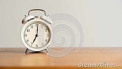 White alarm clock on brown wood desk and cream wallpaper textured background with copy space Stock Photo