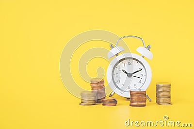 White analog clock white blurred stack of coins on vivid yellow background for business and finance concept Stock Photo