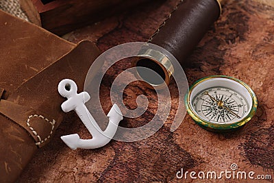 Anchor near leather copy book, compass and telescope on old world map Stock Photo
