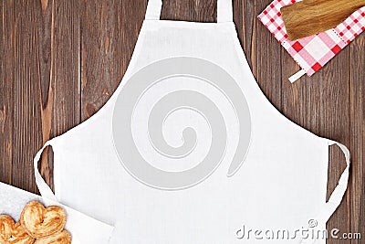 White apron template on brown wooden table with cookies. Kitchen, cooking clothing mock up Stock Photo