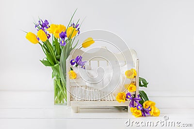 White baby bed for a newborn child on a white background, decorated with yellow tulips and purple irises Stock Photo