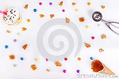 White Background with colorful candies, pieces of waffles, ice cream and empty ice cream cone. Place for lettering. Top view, flat Stock Photo