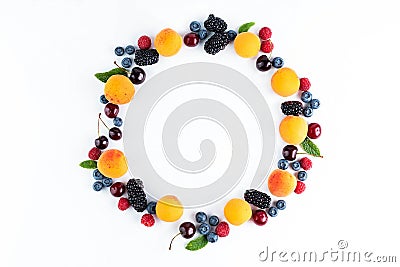 On a white background, fruits are laid out in a circle: apricots, cherries, blackberries, raspberries, blueberries, mint leaves Stock Photo