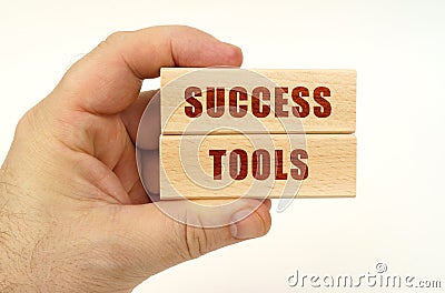 On a white background, a hand that holds wooden blocks with the inscription - Success Tools Stock Photo