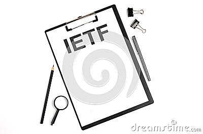On a white background magnifier, a pen and a sheet of paper with the text IETF - Internet Engineering Task Force . Business Stock Photo