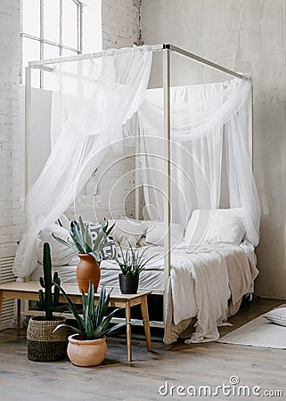 White baldachin over bed in boho chic style bedroom Stock Photo