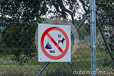 White banner on the netted fence with a red sign - dogs are allowed, pooping is banned Stock Photo
