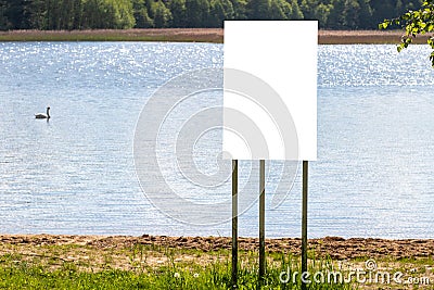 A white banner stands on the lake shore with a mockup Stock Photo