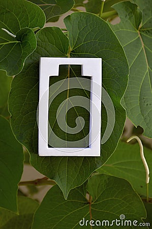 White battery icon on green leaves Stock Photo