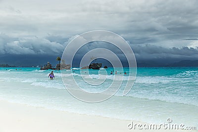 White Beach of Boracay and people swim at turquoise azure Sea on a cloudy day near Grotto Willy`s Rock upon which stands Editorial Stock Photo