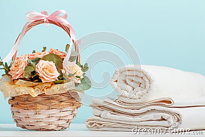 White bed linen sheets roll towels basket with flowers on the table on a blue background Stock Photo