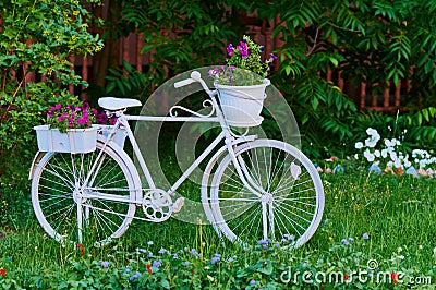 A white bicycle adorns a section of the park. Landscaping. Decorative flowers, grass and bushes. Stock Photo