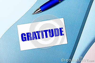 White blank card with GRATITUDE text and blue pen on blue, cyan and pink background Stock Photo