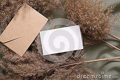 White blank paper card and envelope mockup with pampas dry grass on green neutral colored textile Stock Photo