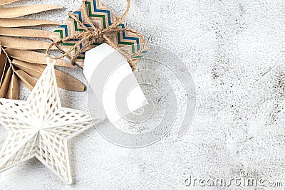 White blank paper tag on craft gifts boxes and Christmas decor on grey conkrete background. Christmas greeting card Stock Photo