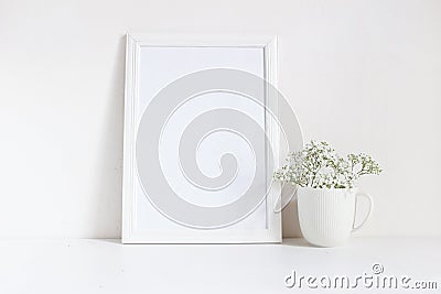 White blank wooden frame mockup with baby breath, Gypsophila flowers in porcelain mug on the table. Poster product Stock Photo