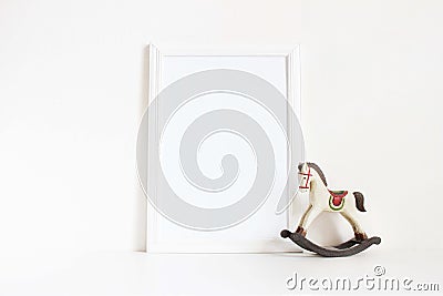 White blank wooden frame mockup with old wooden horse toy on the white table. Styled stock feminine photography. Home Stock Photo