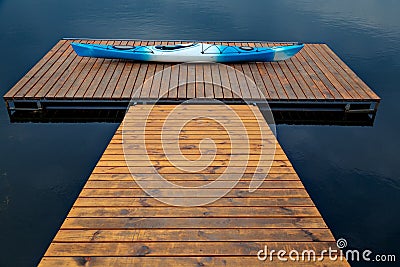 White-blue plastic kayak lying on a wooden dock Stock Photo